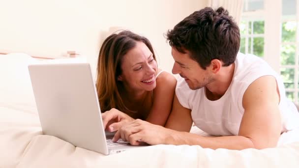 Casal feliz deitado na cama usando laptop juntos — Vídeo de Stock