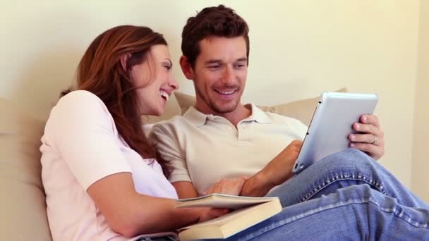 Happy couple sitting on sofa using tablet pc together — Stock Video