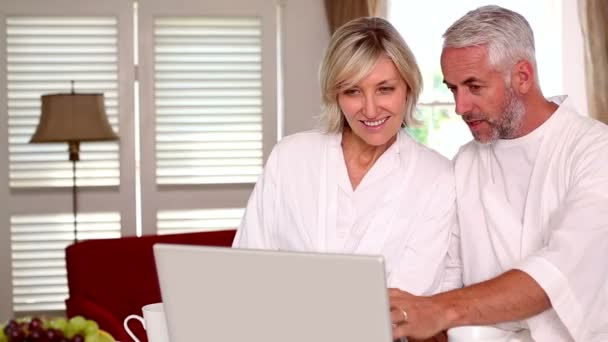 幸せなカップルのバスローブで一緒にラップトップを使用して — ストック動画