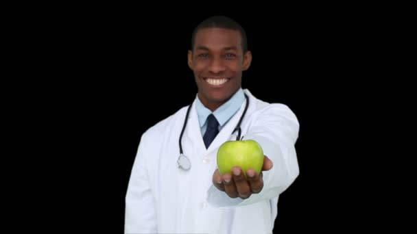 Happy young doctor showing camera an apple — Stock Video