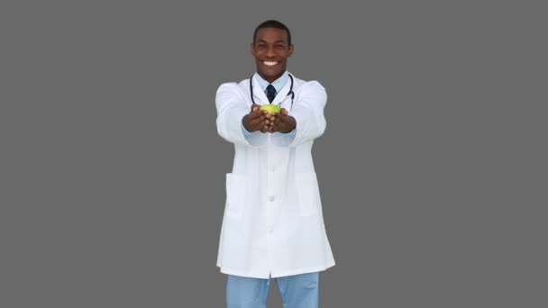 Happy young doctor showing camera an apple — Stock Video