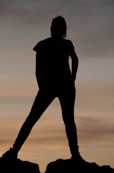 Silhouette einer jungen Frau, die bei Sonnenuntergang auf ein paar Felsen tanzt — Stockfoto