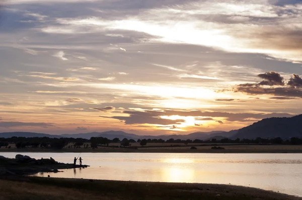两名男子在日落时在湖中捕鱼 — 图库照片