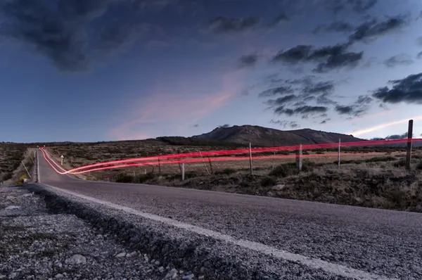 Estela de las luces de un coche en una carretera de montaña al atardecer — Foto de stock gratis