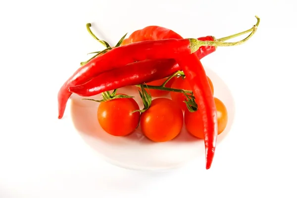 Rode tomaten en paprika op een plaat — Stockfoto