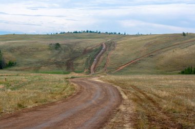 Steppe Tepeleri 'nde bir sürü toprak yol ve araba var. Yatay resim.