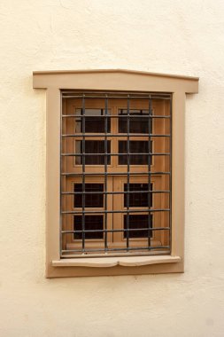 Duvardaki parmaklıklı pencere. Parmaklıkların arkasındaki camlı çerçeve.