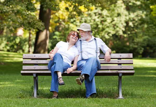 Starší pár sedící na lavičce v parku — Stock fotografie