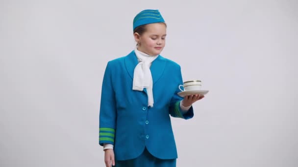 Positief lachend schattig meisje in stewardess uniform poseren met thee kopje koffie op witte achtergrond. Portret van een zelfverzekerde blanke jongen die naar de camera kijkt. Tevredenheid en beroepskeuze. — Stockvideo
