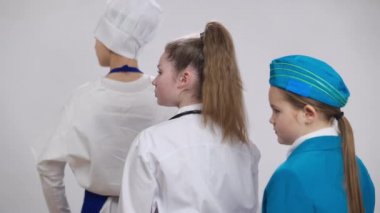 Kafkasyalı ciddi bir doktorun, bulanık küçük hostesle el ele tutuşup beyaz arka planda her iki tarafta yemek pişirdiğinden emin. Tıp mesleği seçen çocuk portresi.