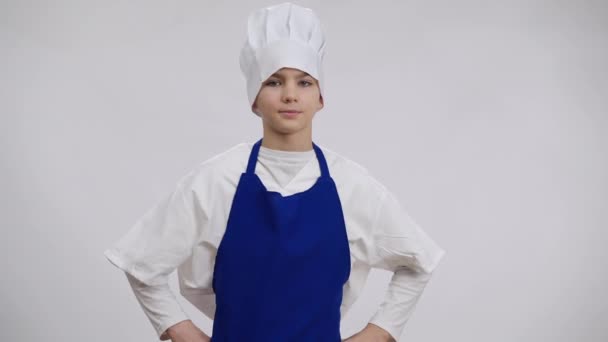 Kleine Köchin zeigt OK Geste lächelnd in die Kamera. Porträt eines positiven selbstbewussten kaukasischen Jungen, der vor weißem Hintergrund mit Hut und Schürze posiert. Berufswahl und Entscheidungskonzept. — Stockvideo
