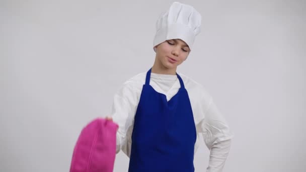 Der kleine stolze Koch seufzt mit hängendem Handtuch auf der Schulter und blickt lächelnd in die Kamera. Porträt eines kaukasischen Jungen mit Kochmütze posiert auf weißem Hintergrund mit zufriedenem Gesichtsausdruck. — Stockvideo