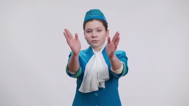 Framifrån av koncentrerad vit flicka visar nödutgångar gester och leende poserar i flygvärdinna uniform på vit bakgrund. Porträtt av självsäker unge väljer flygvärdinna yrke. — Stockvideo