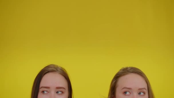 Yeux de sœur jumelle en bas se déplaçant avec l'espace de copie fond jaune. Identique Caucasien jeunes beaux jumeaux posant à fond coloré. Concept de publicité. — Video