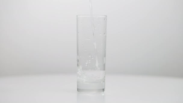 Water gieten in glas morsen op tafel close-up Onherkenbaar persoon morst vloeistof in slow motion close-up. — Stockvideo
