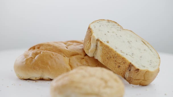 Deliziosa pasticceria al forno sdraiata sul tavolo su sfondo bianco come gustoso dolce panino che cade al rallentatore. Primo piano del pane al chiuso. — Video Stock