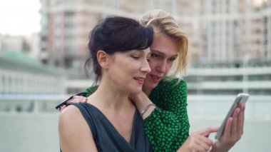 Neşe dolu yetişkin kadınlar akıllı telefonda sosyal medyada kayar yavaş çekimde gülerek konuşurlar. İnternet 'te sörf yapan neşeli Kafkas arkadaşlarının portresi. Şehir caddesinde hafta sonunun tadını çıkarıyorlar..