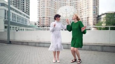Güzel elbiseli, neşeli, zarif kadınlar şehir sokaklarında ağır çekimde dans ediyorlar. Heyecanlı, mutlu, beyaz, zayıf ve çekici arkadaşların portresi. Hafta sonları dışarıda buluşup eğleniyorlar..