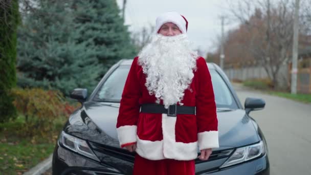 Positiva glada jultomten skryta bilnycklar står på fordonet utomhus tittar på kameran. Porträtt av glad vit ung man i röd kostym poserar på förortsgatan visar upp. — Stockvideo