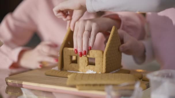 Nierozpoznawalna matka i córka robiące domek imbirowy w domu w Wigilię. Biała kobieta i dziewczyna przygotowują pyszny tradycyjny słodki deser na Nowy Rok. Kulinarne i rodzinne. — Wideo stockowe