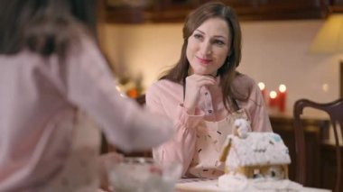 Mutfakta zencefilli evde yemek pişiren kızına hayran olan mutlu bir anne. Zayıf, çekici, beyaz bir kadının yeni yıl arifesinde tanınmayan bir kızla konuşmasının portresi.