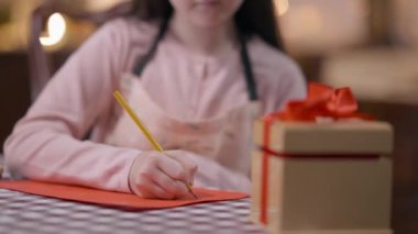 Yılbaşı arifesinde evde Noel Baba 'ya mektup yazan tanınmamış bir kız. Kafkas çocuk el yazısı önlüklü masada oturmuş Noel tatiline hazırlanıyor..