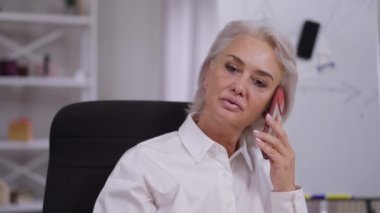 Ofiste ağır çekimde telefonla konuşan zeki, kendine güvenen bir iş kadınının portresi. Profesyonel Kafkas kadın CEO 'su iş planlama stratejisini tartışıyor.