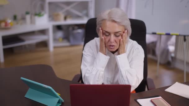 Exhausted troubled middle aged businesswoman holding head in hands sighing looking at camera shaking head. Portrait of tired Caucasian mature woman sitting in office dealing with problem. — Stock Video