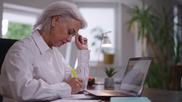 측면에서는 사려 깊은 백인 성숙 한 여성 이 사무실에 앉아 있는 사업의 수익성을 분석하고 있습니다. 펜 계획 전략으로 글을 쓰는 자신 감넘치는 여성 CEO 의 모습. — 비디오