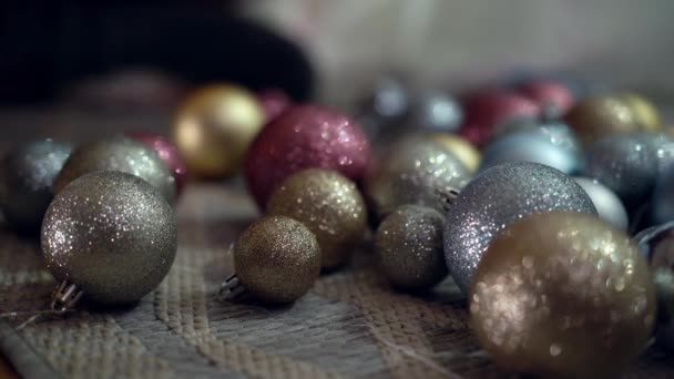 Close-up Christmas decorations lying on floor sparkling with female Caucasian hand taking one ball. Unrecognizable woman decorating house on New Years eve indoors. Holidays concept. — Stock Video