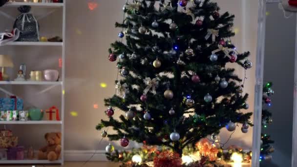 Versierde kerstboom in de woonkamer met lichtjes die binnen schijnen. Nieuwjaar feestelijk humeur zonder mensen. Vakantie tradities en viering concept. — Stockvideo