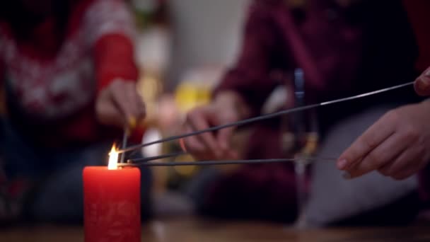 Rode kerstkaars met sterretjes in de handen die binnen oplichten. Onherkenbare groep vrienden of familie vieren Nieuwjaar in de woonkamer. Geluk en vreugde concept. — Stockvideo