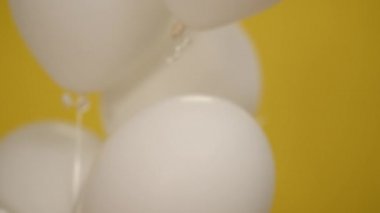 Beyaz balonda plastik yok. Beyaz tenli kadın eli ağır çekimde iğne ile topu patlatıyor. Sarı arka planda ekolojik zarar sembolü olan tanınmayan bir kadın..