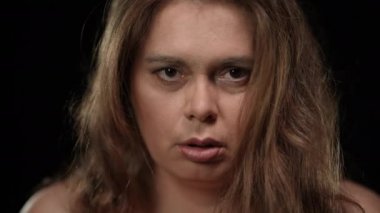 Vesikalık portre, aşırı kilolu bir kadının kameraya bakarak bant çiğnemesi yüzünden bunalmış. Siyah arka planda poz veren üzgün, beyaz, obez kadının ön yüzü..