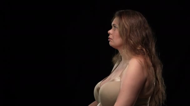 Boční pohled smutná obézní žena ve spodním prádle dívající se na kameru odvracející sepjaté ruce modlí. Nešťastný běloch plus velikost dáma na černém pozadí na pravé straně. — Stock video