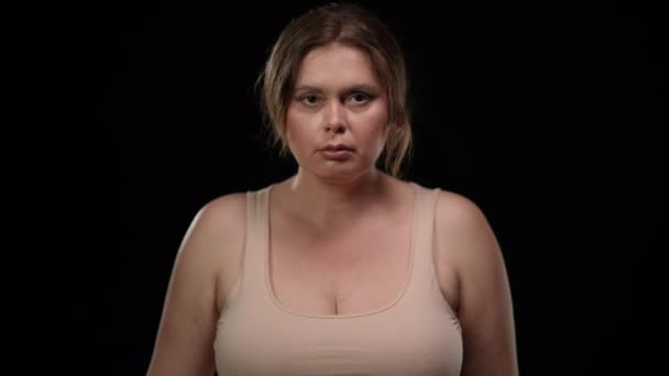 Vážná plus velikost žena, která zvedá ruku na prsa a nadává na černém pozadí. Portrét obézní bělošské brunetky dívající se do kamery. Koncept důvěry. — Stock video