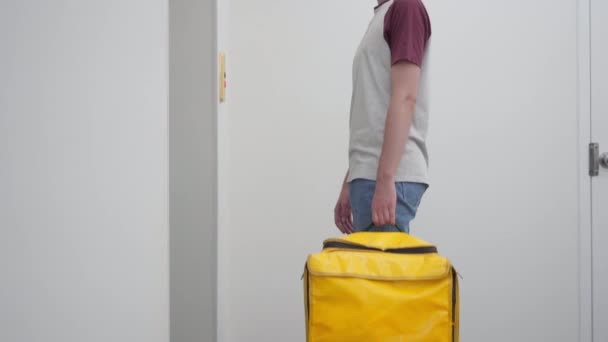 Pedestal side view young courier with thermal backpack waiting for elevator in house or business center. Caucasian man working delivering takeaway food in urban city standing indoors at lift. — стоковое видео