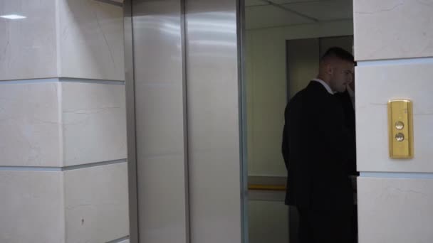 Confident handsome young businessman entering elevator pressing button and lift door closing. Portrait of successful Caucasian man in black formal suit in business center indoors. — Stockvideo