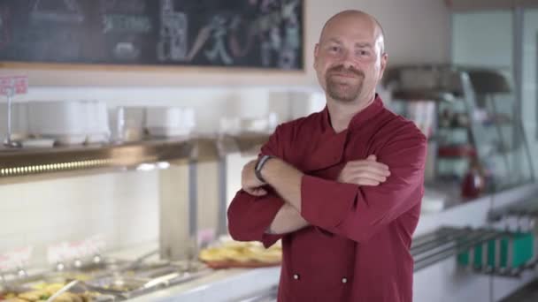 Portrait of confident Caucasian man crossing hands smiling looking at camera standing in self service canteen. Satisfied cafeteria cook posing indoors. Food and drink industry concept. — Stok video