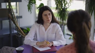 Meraklı İK müdürünün portresi. Kapalı bir kafede oturan başvuruyu dinleyen kişinin portresi. Kafkasyalı bir kadın kahvede gülen bir çalışanla röportaj yapıyor. İstihdam ve yaşam tarzı kavramı.