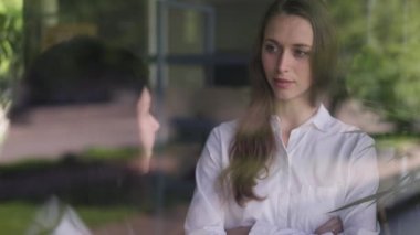 Yavaş çekimde konuşan iki kadın meslektaşın camına ateş ederek içeride strateji fikrini tartışıyorlar. Ofiste iş planlayan konsantre, zeki, beyaz kadınlar. Yavaş çekim.