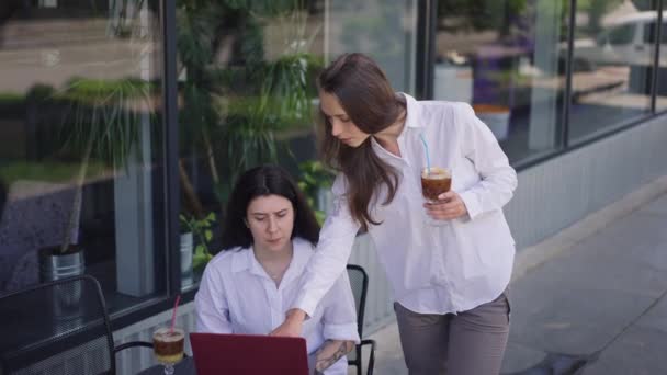 To selvsikre unge kvinder diskuterer start projekt på cafe sommer terrasse med drikkevarer. Koncentreret kaukasiske kolleger brainstorming på frokostpause udendørs taler planlægning strategi ide. – Stock-video