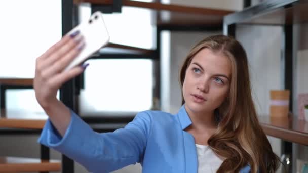 Elegancka pewna siebie młoda piękna kobieta robi selfie na smartfonie stojącym w domu. Portret zadowolonego, szczęśliwego, białego menedżera fotografującego w nowym, formalnym garniturze uśmiechniętym. — Wideo stockowe