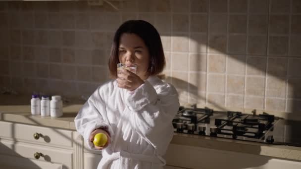 Sağlıklı Vitaminli Limon Suyu Içen Küçük Bir Kadın Mutfakta Meyvelerle — Stok video