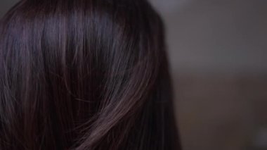 Saçlarını tarayan küçük bir kadının eliyle yakın çekimde esmer saçlar. Evde saç tıraşı olan tanınmamış genç bir adam.
