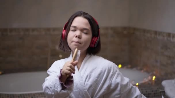 Sorglos Entspannte Kleine Frau Mit Kopfhörern Die Drinnen Der Haarbürste — Stockvideo