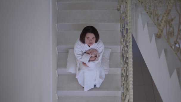 俯瞰悲伤的小女孩坐在楼梯上抱着玩具思考 身穿白色浴衣 家里有柔软玩具的白人小孩很不高兴 — 图库视频影像