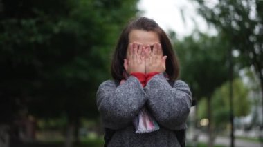 Elleriyle yüzünü kapatan beyaz bir kadın bulutlu yağmurlu bir günde açık havada dilek diliyor. Canlı kamera yavaş çekimde poz veren sevimli küçük insanın yüzünü yakınlaştır