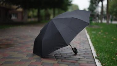 Şehir caddesinde açık hava bulutlu bir günde siyah şemsiye uzanıyor. Yağmur aksesuarları kasabada kayboldu. Yavaş çekim