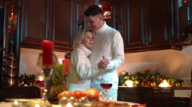Loving romantic husband and wife dancing in kitchen at home indoors. Smiling happy Caucasian man and woman hugging enjoying holiday celebration. Comfort and love concept